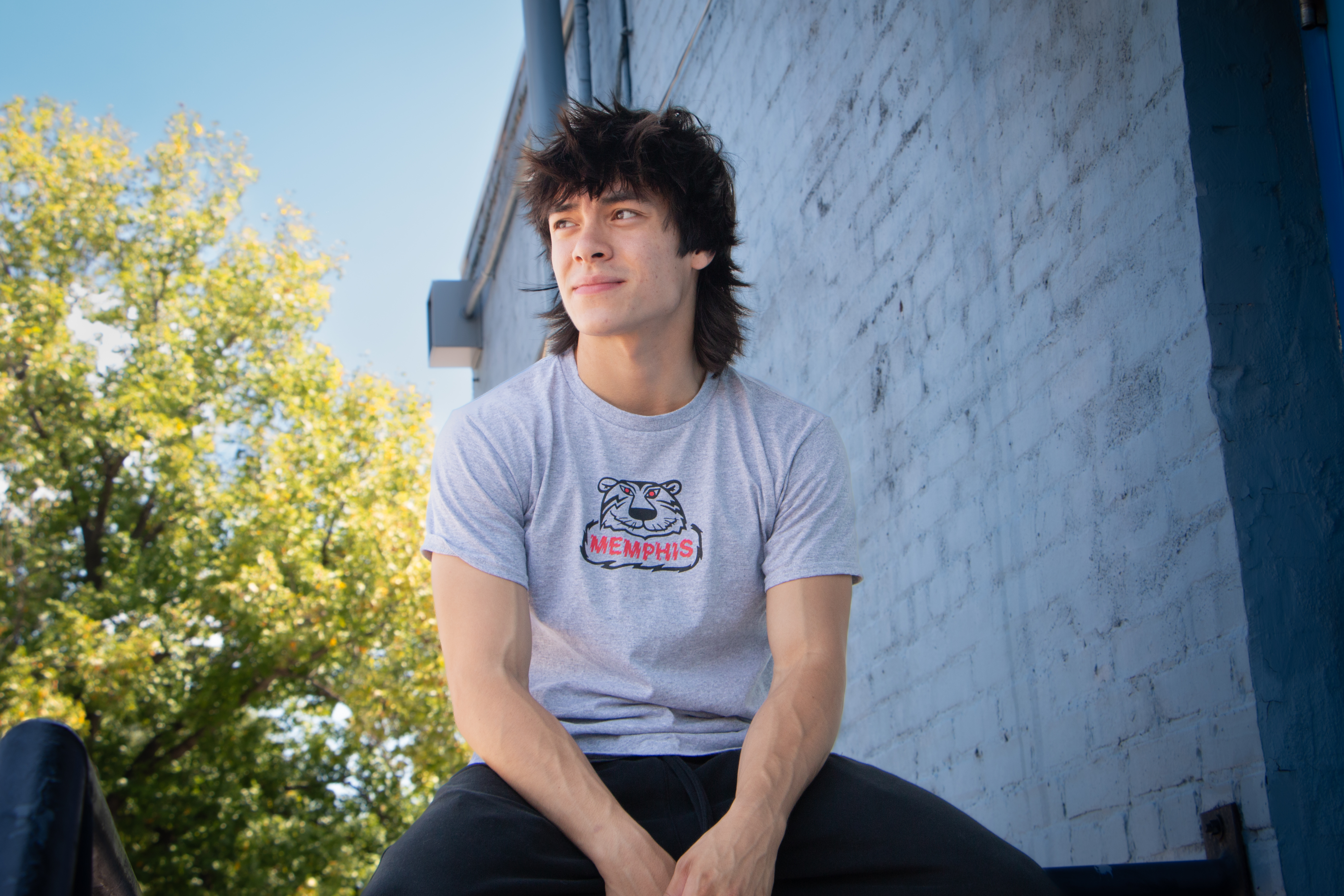 Memphis musician, Aidan Osias, sitting on a railing